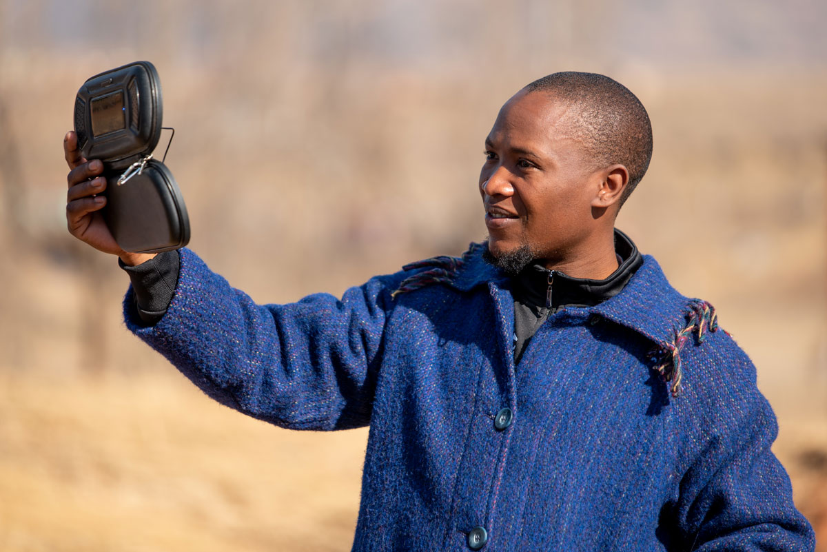 African man plays translated audio Scriptures on a portable solar powered device